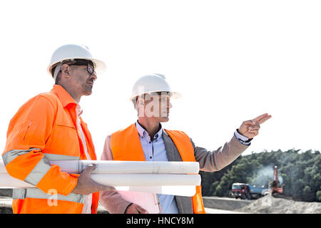 Male engineers discussing at construction site against clear sky Stock Photo