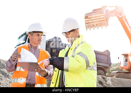 Engineers discussing over documents at construction site Stock Photo