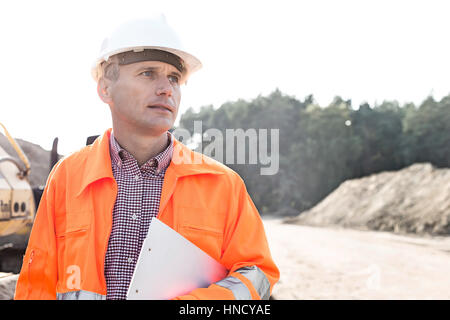 Thoughtful engineer holding clipboard against clear sky Stock Photo