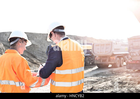 Engineers writing on clipboard at construction site against clear sky Stock Photo