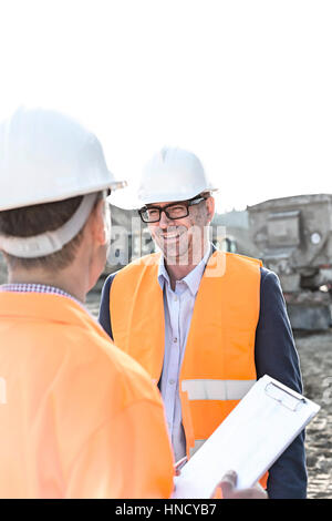 Happy engineers discussing at construction site against clear sky Stock Photo