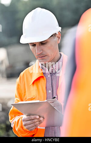 Supervisor writing on clipboard at construction site Stock Photo