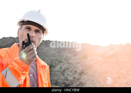 Confident supervisor using walkie-talkie on construction site against clear sky Stock Photo
