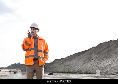 Confident male supervisor using walkie-talkie on construction site against clear sky Stock Photo