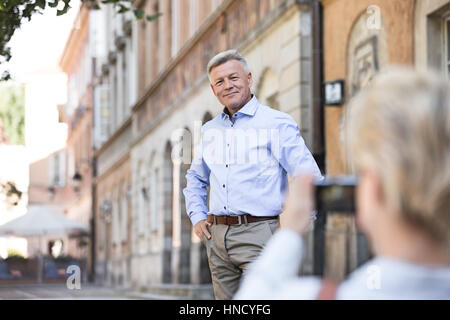 Middle-aged woman taking picture of man in city Stock Photo