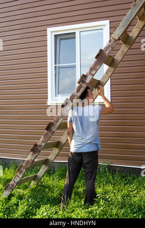 man puts a wooden staircase to the house Stock Photo