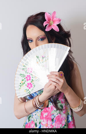 Beautiful young woman hiding her face with a fan Stock Photo