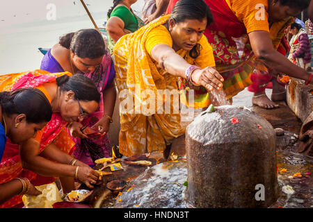 Women, Pilgrims making a ritual offering, and praying, ghats in Ganges river, Varanasi, Uttar Pradesh, India. Stock Photo