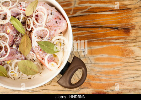 raw rabbit on a wooden Board with ingredients for stewing onion, pepper, bay leaf, rosemary and knife on a wooden background - top view Stock Photo