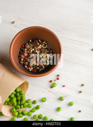 Pepper and spices in a bowl. Green peas in paper bag. Copy space. Stock Photo