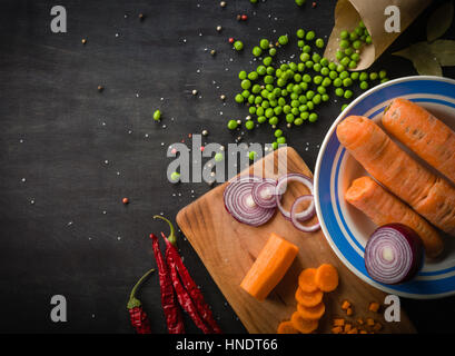 Cooking a meal of fresh vegetables. The composition on a dark wooden background. Top view, space for text Stock Photo