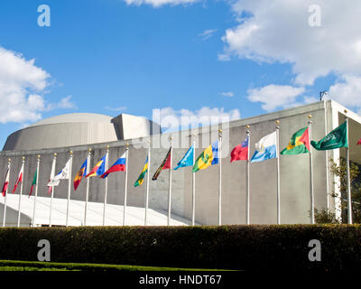 A row of flags waving in front of the United Nations Headquarters building in downtown New York City.