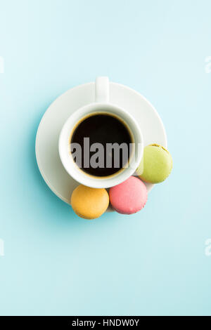 Tasty sweet macarons and coffee cup. Macaroons on blue background. Top view. Stock Photo