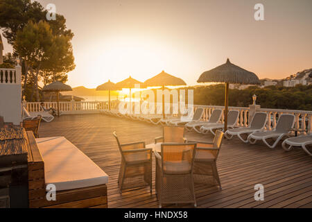 table and chairs in sunset on terrace of summer holiday resort Stock Photo