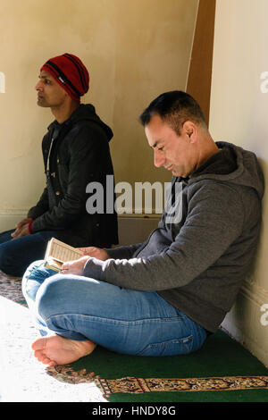 A man reads the Qu'ran in a Mosque Stock Photo