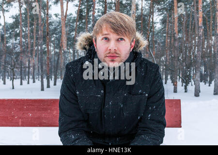 Thoughtful young man. A young man sits on a bench and thinks. Stock Photo