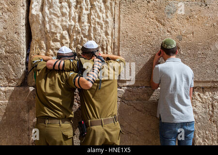 Wailing Wall, Western Wall, men, soldiers and a civil man praying, men's prayer area, Jewish Quarter, Old City, Jerusalem, Israel. Stock Photo