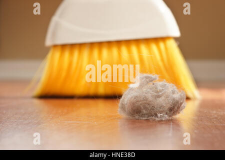 Yellow broom sweeping a giant dust ball Stock Photo
