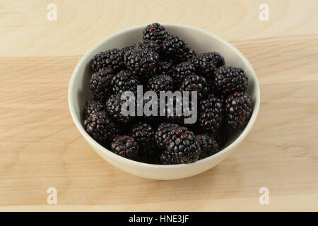 Blackberries in white bowl on wooden table Stock Photo