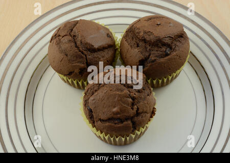 Three sugarless chocolate chip chocolate muffins or cupcakes without frosting on plate Stock Photo