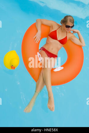 Model release, Junge Frau im Bikini entspannt im Schwimmreifen im Pool - young woman with floating tire in swimming pool Stock Photo