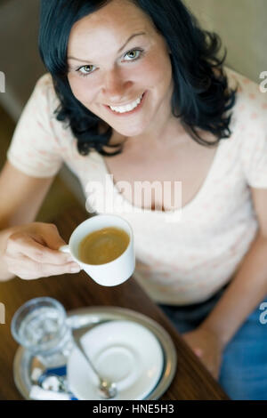 Model release, Junge Frau im Kaffeehaus trinkt Kaffee - young woman in cafeteria drinks coffee Stock Photo