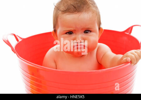 Model release, Kleinkind, 8 Monate, sitzt in roter Wanne und macht ein lustiges Gesicht - little child with funny face in red tub Stock Photo