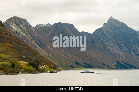 A small car ferry links the villages of Urke and Sæbø on opposite sides of Hjørundfjorden fjord.  Here the ferry approaches Urke. Stock Photo