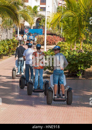 Four men ride on Segways on the promenade at the up market resort of Costa Adeje Tenerife Canary Islands Stock Photo