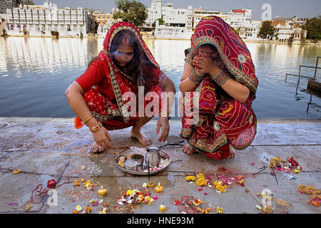 Girls praying, making a offering,in Gangaur ghat,Pichola lake,Udaipur, Rajasthan, india Stock Photo