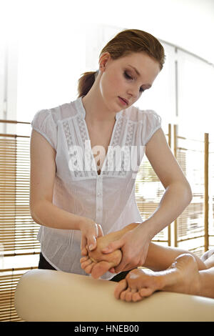 Young woman receiving foot massage from masseuse Stock Photo