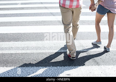 Low section of couple walking on crosswalk Stock Photo