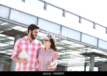 Happy couple looking at each other while walking in city Stock Photo