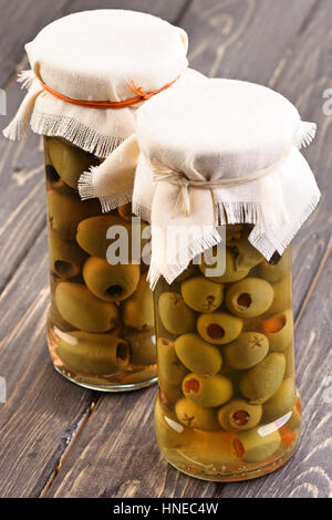 Pickled olives in jar on wooden table Stock Photo