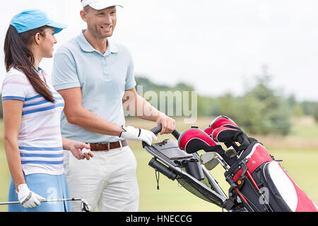 Happy friends with bag talking at golf course Stock Photo