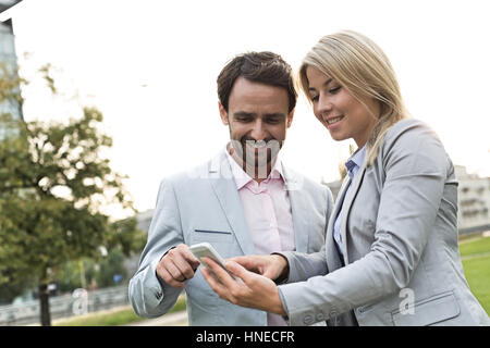Happy business couple using smart phone at park Stock Photo