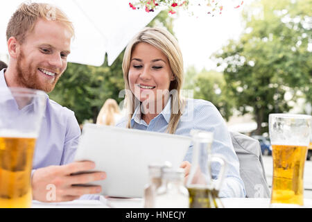 Happy businesspeople using digital tablet at sidewalk cafe Stock Photo