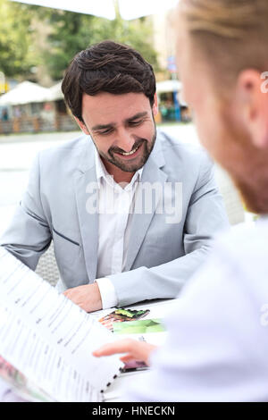 Businessmen deciding menu at sidewalk cafe Stock Photo