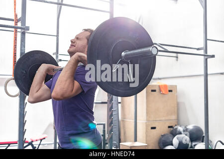 Confident man lifting barbell in crossfit gym Stock Photo