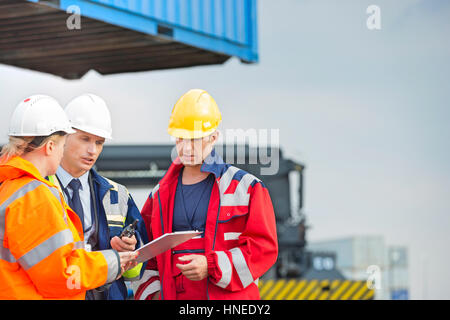 Workers discussing over clipboard in shipping yard Stock Photo