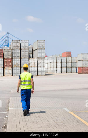 Full-length rear view of male worker walking in shipping yard Stock Photo