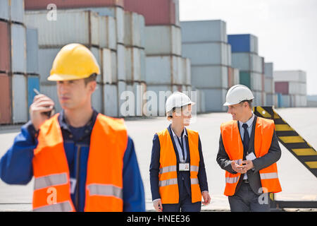 Worker using walkie-talkie while colleagues discussing in shipping yard Stock Photo