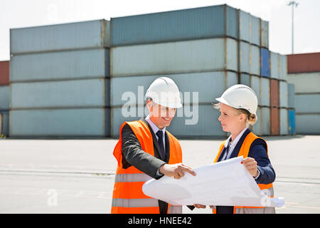 Engineers looking at blueprint in shipping yard Stock Photo