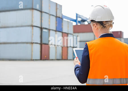 Rear view of female engineer using digital tablet in shipping yard Stock Photo