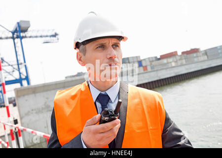 Middle-aged man using walkie-talkie in shipping yard Stock Photo