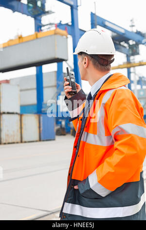 Middle-aged man using walkie-talkie in shipping yard Stock Photo