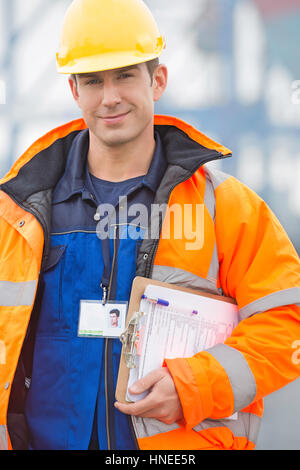 Portrait of confident mid adult man with clipboard in shipping yard Stock Photo