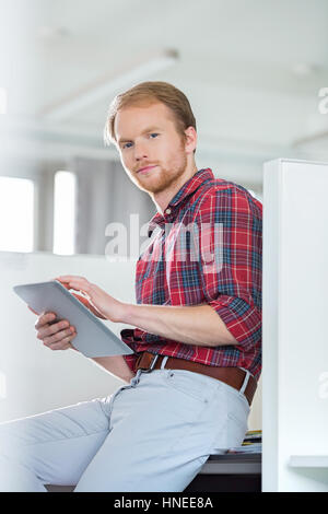 Portrait of confident businessman using tablet PC in creative office Stock Photo