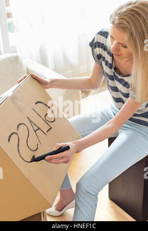 Woman labeling moving box with glass material at home Stock Photo
