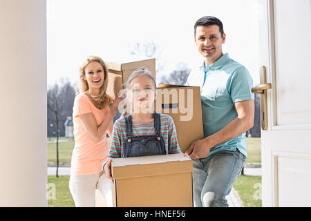 Happy family with cardboard boxes entering new home Stock Photo
